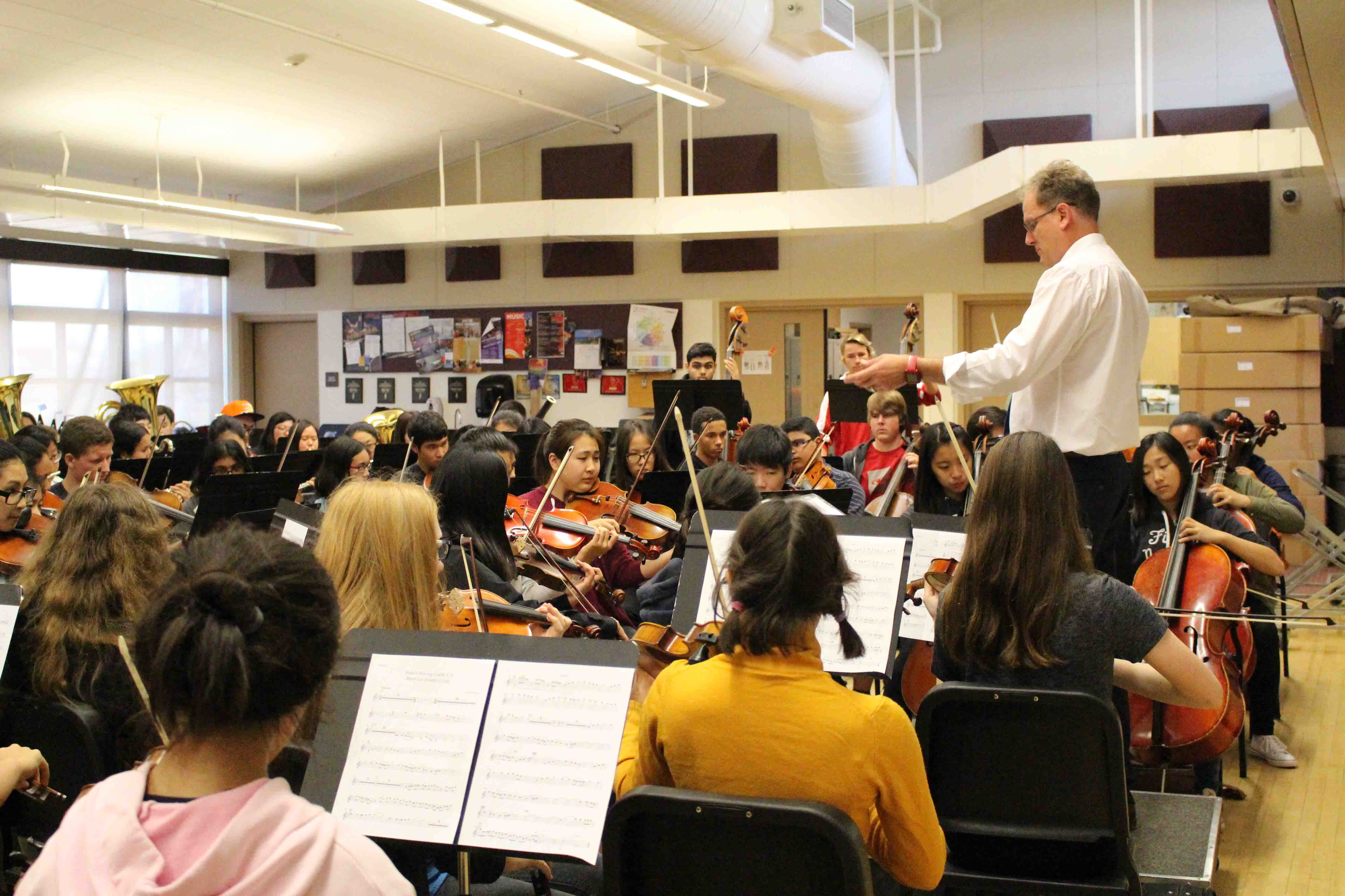 Music teachers Brad Harris conducts Symphonic Orchestra, setting the tempo of the piece as students follow his lead.
