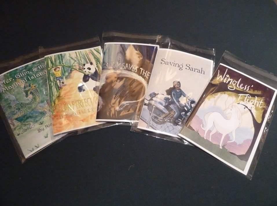 Senior Bryce Morgan displays examples of the books that were written based off the children in the hospital with the covers designed by the illustrators.
