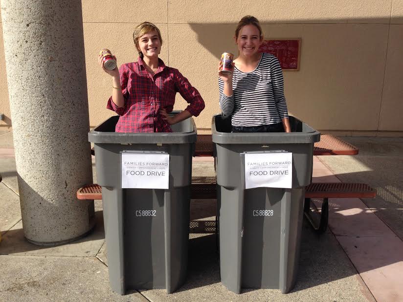 Seniors+Kelsey+Eyre+and+Jennifer+Borland+pose+in+collecting+bins+in+order+to+encourage+students+to+donate+cans+for+the+can+drive.+
