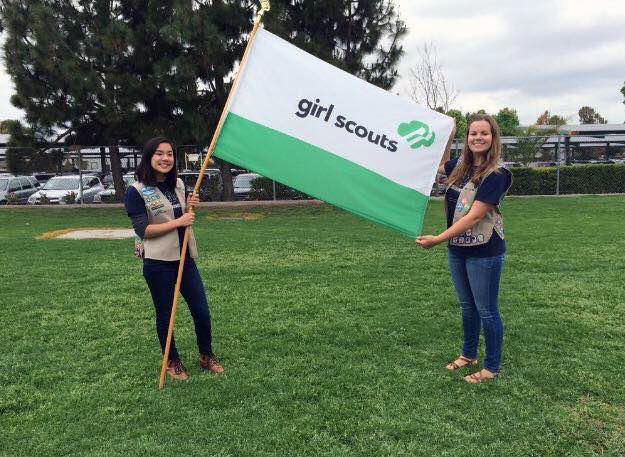 Senior Jackie Murray (right) and fellow troop member Veronica Chang (left) participate in the flag ceremony during the Girl Scouts International Day event.