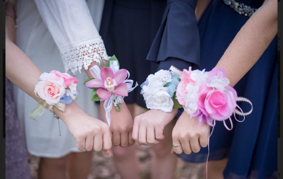A group of students who went to Winter Formal posed for a picture with their corsages as a part of Winter Formal tradition. 