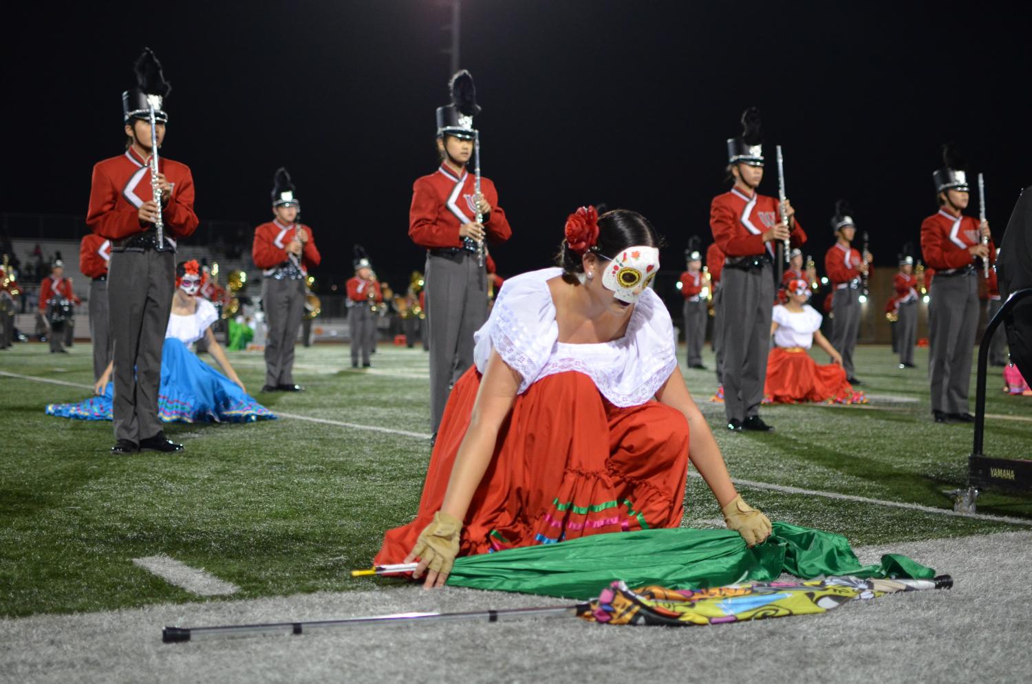 Colorguard performer, Alexis Chirco, senior, sets down her flag and takes a deep breath as she begins the next segment of the halftime show.