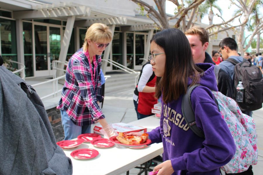 “Pizza Friday” staff members hand out tickets and pass out pizza to students.