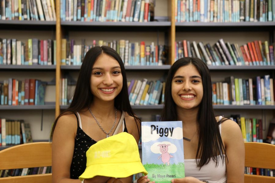 Senior Isha Pasari and junior Maya Pasari proudly show off their picture book and hat they made for their non-profit.