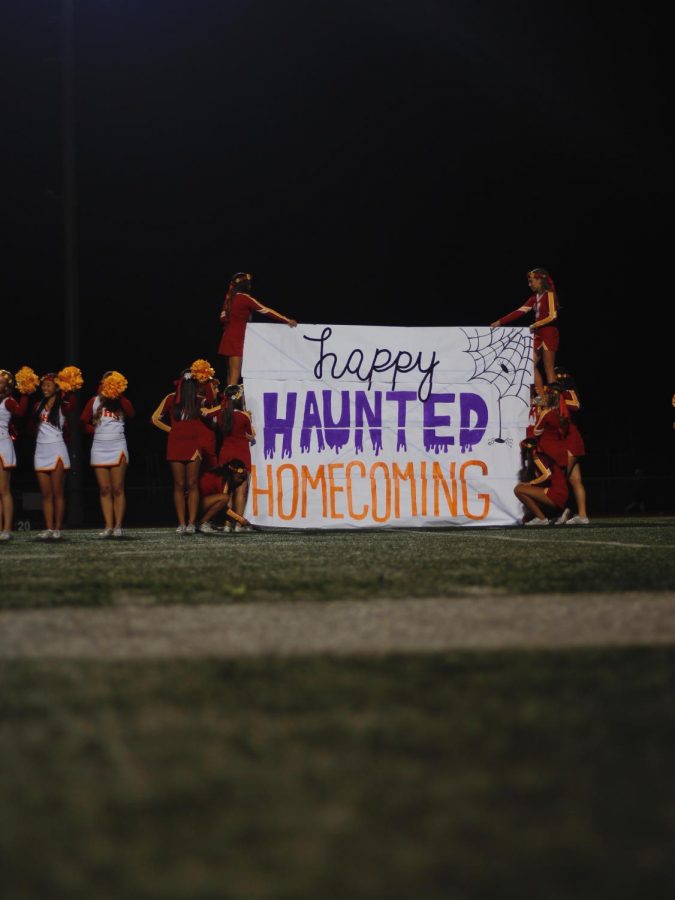 The cheerleaders present the Haunted Homecoming Football sign for all to see. 	