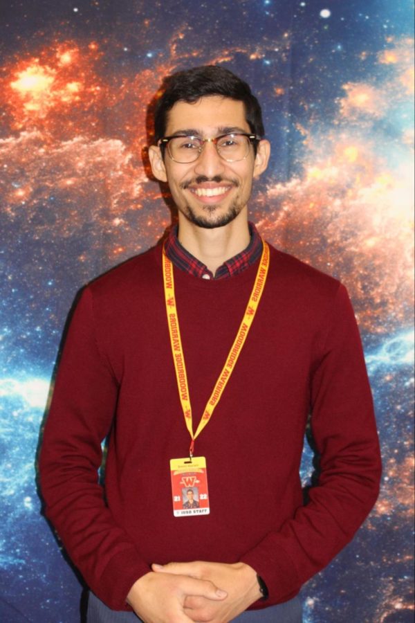Science teacher Dimitri Kaviani poses in front of his galaxy poster.