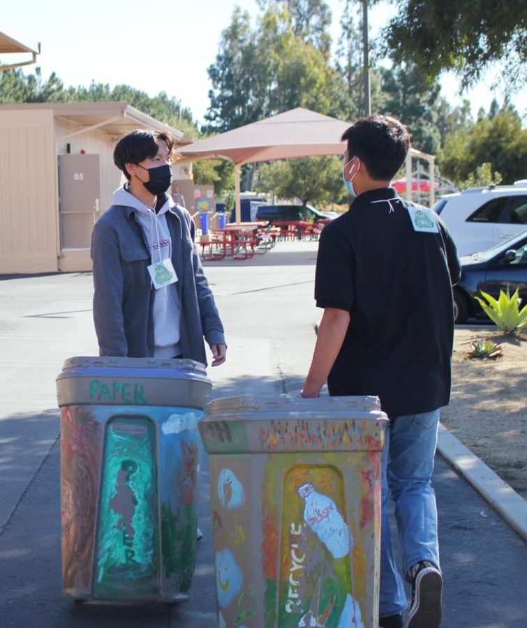 Recycling Club president Caleb Jang and member Ryan Miao bring bins to dumpster to recycle.