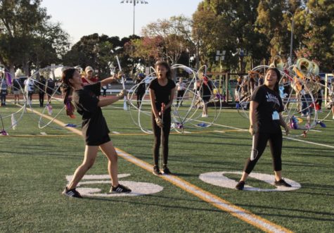 Varsity color guard member Chloe Tomsen (on the left) successfully catches a toss.