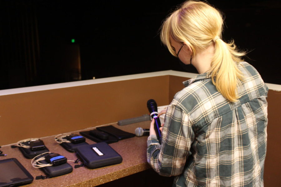 A Tech Theater student shows other students how to replace batteries in a wireless microphone. 