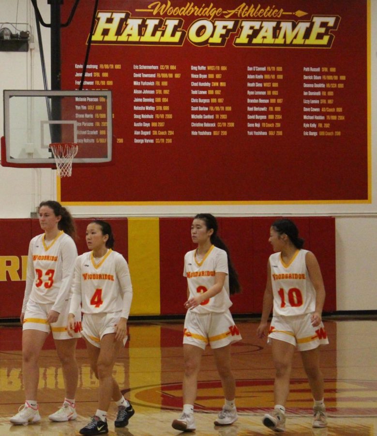 Woodbridge High’s girls’ varsity basketball team steps off the court to discuss the game plan during a time out.