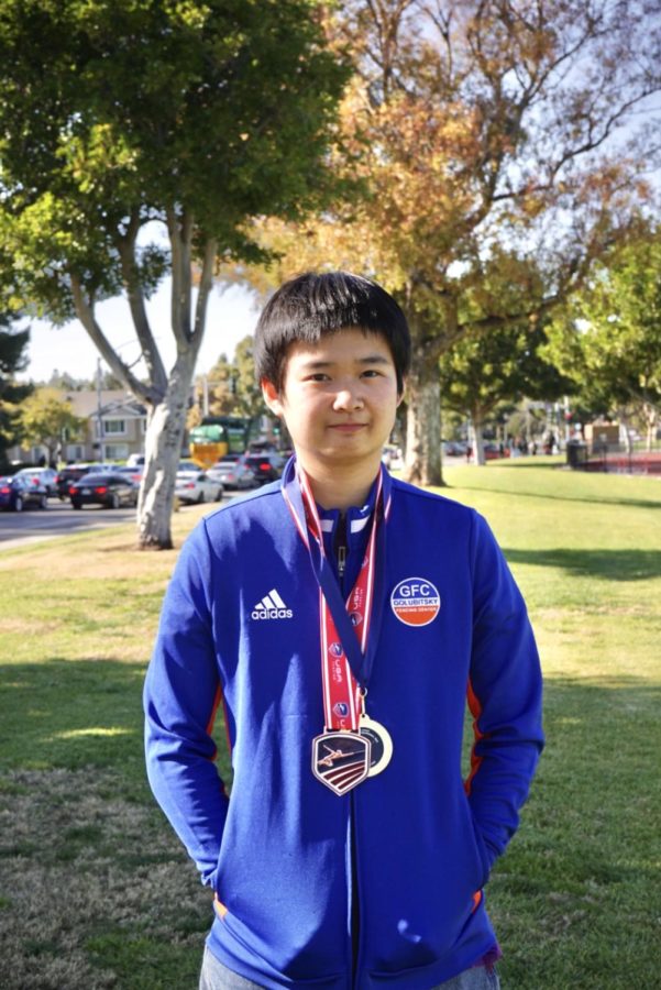 Senior Amber Peng, a recipient of numerous
awards from various fencing tournaments and
competitions, poses with her fencing tracksuit
and medals.