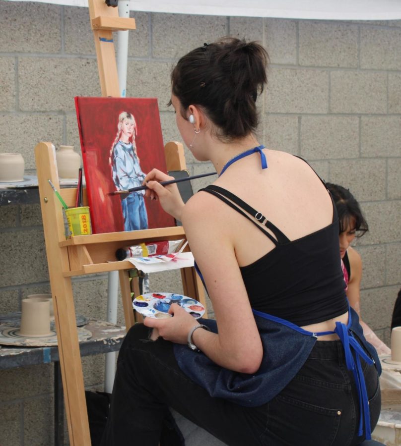Junior Camille Conde adds the finishing paint strokes to her artwork.
