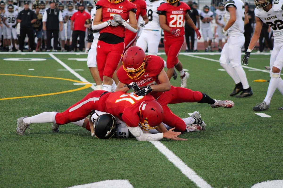 Woodbridge High varsity football players tackle an opposing player.