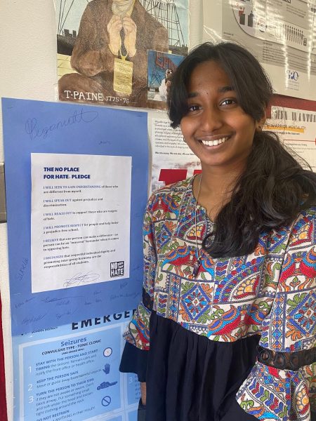 No Place for Hate Junior, Amritha Boddhu, stands by the sign that every student signed, pledging to add to a safe and kind environment at Woodbridge. 