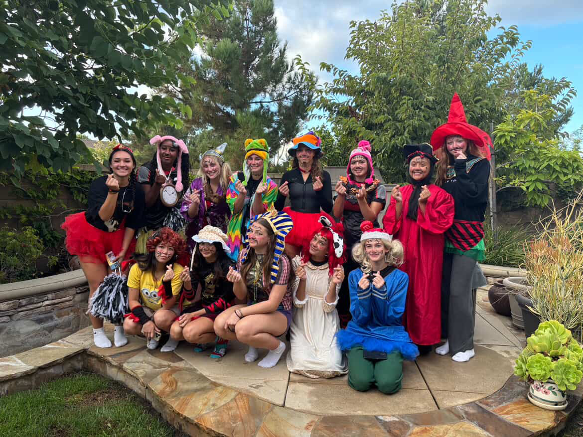 Girls varsity volleyball initiates pose together in a variety of unique costumes, showcasing their dedication to the team. 