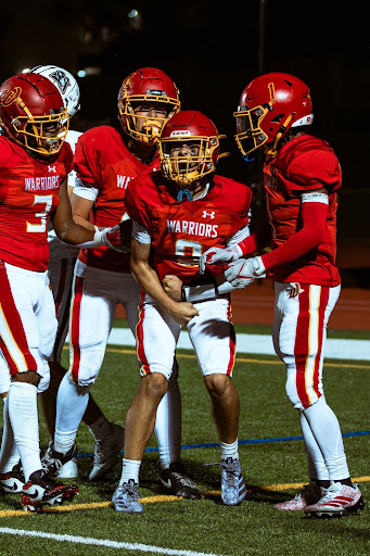 Woodbridge High football players celebrate after a touchdown on the Warrior home field. 